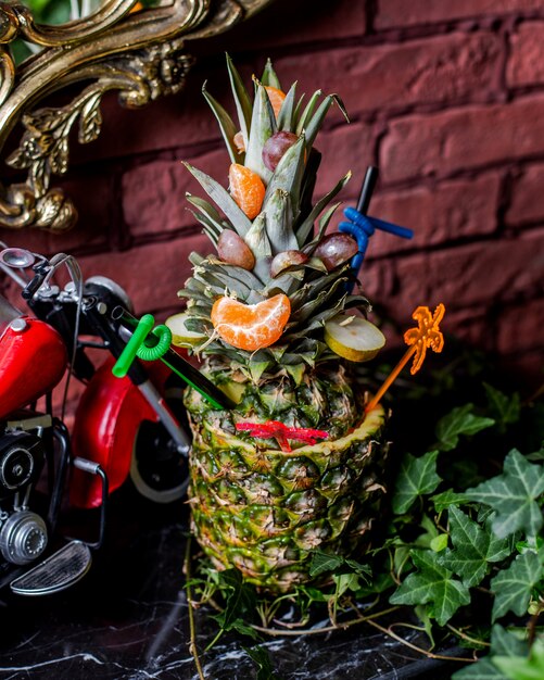 Ananascocktail serviert in Ananas mit Mandarinen- und Birnenscheiben