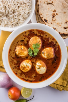 Anda curry oder egg masala soße, indisches scharfes essen oder rezept, serviert mit jeera reis, roti oder naan, selektiver fokus. über bunter oder hölzerner tischplatte