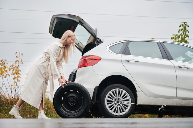 Kostenloses Foto angehaltenes weißes auto mit durchstochenem autoreifen auf einem straßenrand