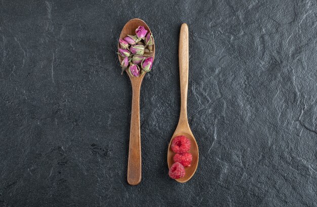 Angehende Rosen und Himbeeren auf Holzlöffeln.