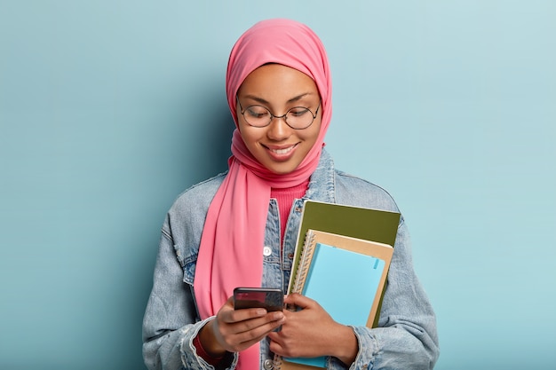 Kostenloses Foto angenehm aussehende lächelnde frau, eingewickelt in rosa schleier, studiert am college