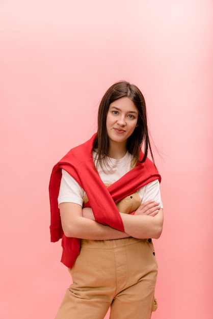 Angenehme junge kaukasische brünette Frau in Freizeitkleidung blickt mit gefalteten Händen in die Kamera Lifestyle-Modekonzept