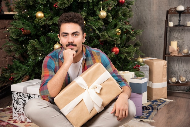 Angenehmer Mann, der eine Geschenkbox hält und lächelt.