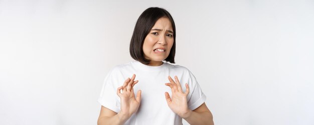 Angewiderte asiatische Frau, die etw ablehnt, verzieht das Gesicht aus Abneigung und Abneigung, starrt mit zurückschreckender Ablehnung an