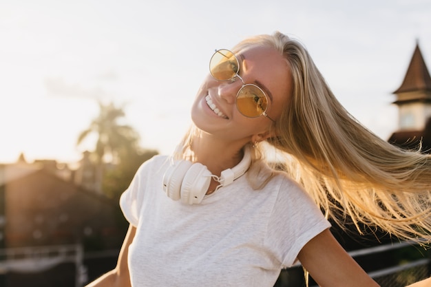 Anmutige Frau in der gelben Sonnenbrille, die das Leben im Sommerabend genießt.