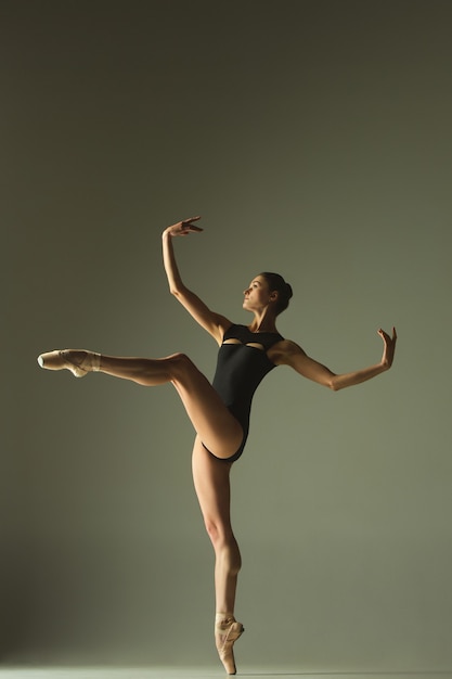 Anmutiger Balletttänzer oder klassischer Ballerina-Tanz lokalisiert auf grauem Studiohintergrund. Flexibilität und Anmut zeigen. Das Tanz-, Künstler-, Zeitgenossen-, Bewegungs-, Aktions- und Bewegungskonzept.