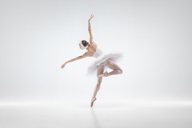 Anmutiger klassischer Ballerina-Tanz lokalisiert auf weißem Studiohintergrund. Frau in zarten Kleidern wie ein weißer Schwan Charaktere. Das Konzept von Anmut, Künstler, Bewegung, Aktion und Bewegung. Sieht schwerelos aus.
