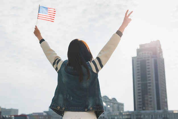 Anonyme frau, die hände und amerikanische flagge zu ehren des unabhängigkeitstags anhebt