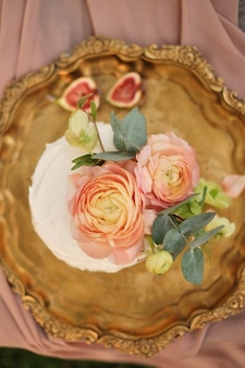 Anordnung für den rosa kuchen, der mit ranunculusblumen verziert wird Premium Fotos