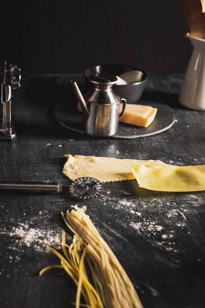 Anordnung mit Teig für Spaghettis auf schwarzer Tabelle