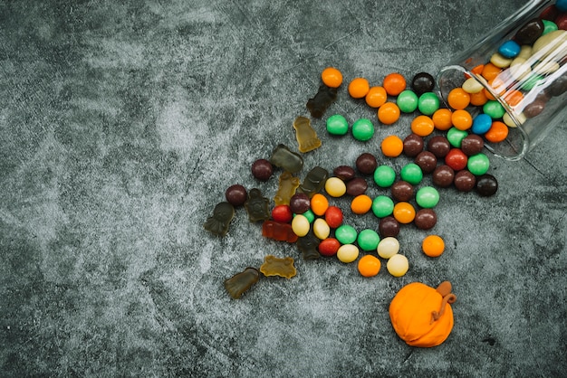 Kostenloses Foto anordnung mit zerstreuten bonbons und süßigkeitkürbis