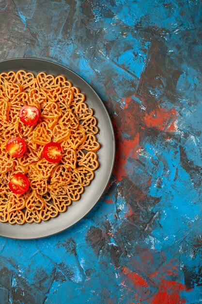 Ansicht der oberen Hälfte italienische Pasta Herzen schneiden Kirschtomaten auf schwarzem ovalen Teller