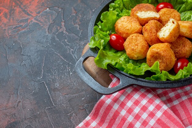 Ansicht der unteren Hälfte Chicken Nuggets Salat Kirschtomaten in Pfanne auf dunklem Hintergrund