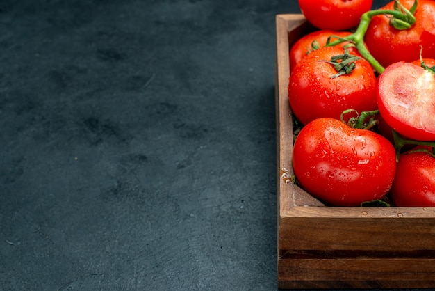 Ansicht der unteren Hälfte rote Tomaten in Holzkiste auf schwarzem Tisch mit Kopierraum