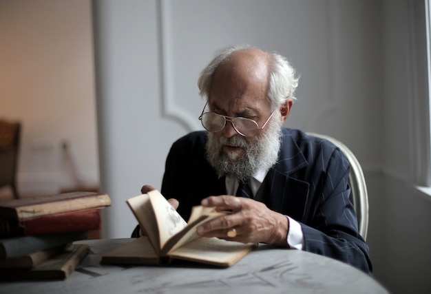 Ansicht eines alten kaukasischen Mannes, der ein antikes Buch in einem Raum liest