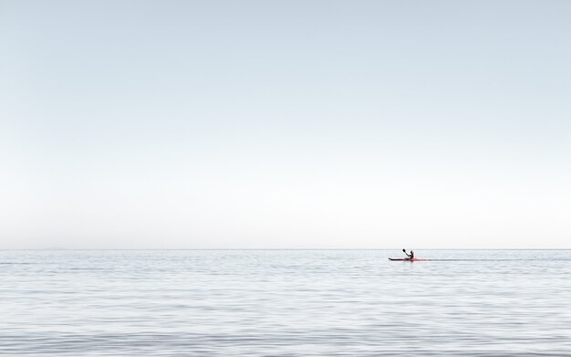 Ansicht eines Mannes, der auf dem sehr ruhigen Wasser auf dem Meer Kajak fährt