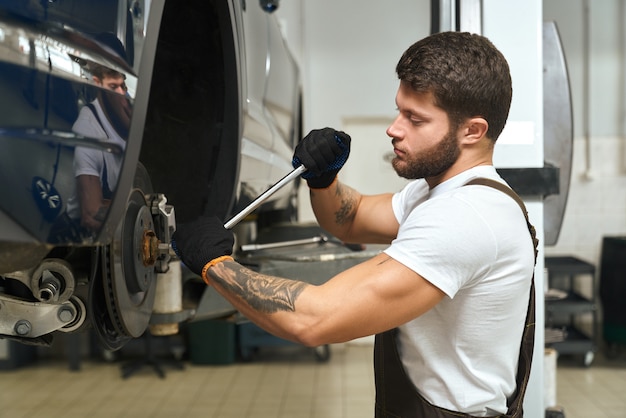 Ansicht von der Seite des gutaussehenden Mannes, der Reifen des Autos wechselt