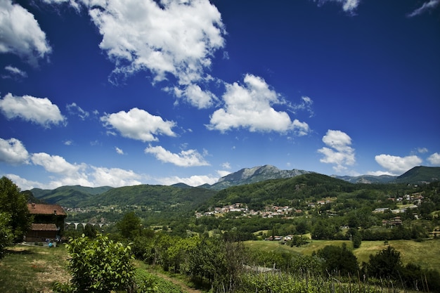 Ansicht von Häusern auf grünen Hügeln mit einem bewölkten blauen Himmel im Hintergrund