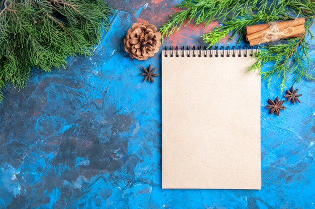 Ansicht von oben ein Notizbuch Pine Tree Branches Sternanis auf blauem Hintergrund mit freiem Speicherplatz