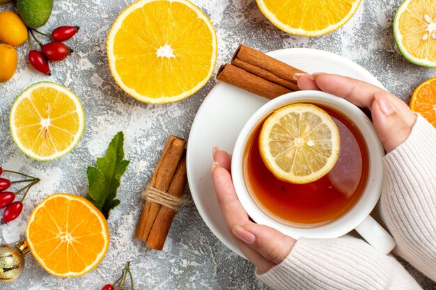 Ansicht von oben eine Tasse Tee mit Zitronenscheibe geschnittenen Zitronen Zimtstangen auf grauem Hintergrund