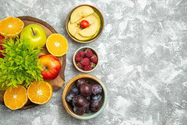 Ansicht von oben frische Äpfel mit geschnittenen Orangen und Pflaumen auf weißem Hintergrund reife reife Früchte frischer Apfel