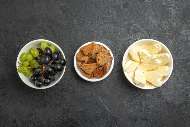 Ansicht von oben frische, weiche Trauben mit Brot und Käse auf der dunklen Oberfläche Lebensmittelmahlzeit Milchfrucht