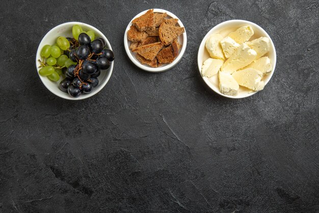 Ansicht von oben frische, weiche Trauben mit Brot und Käse auf der dunklen Oberfläche Lebensmittelmahlzeit Milchfrucht