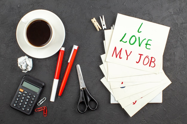 Kostenloses Foto ansicht von oben ich liebe meinen job geschrieben auf notizpapier wäscheklammern schere taschenrechner tasse tee roter stift und marker auf schwarz