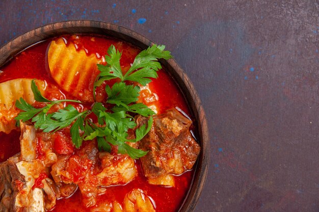 Ansicht von oben in der Nähe köstliche Fleischsauce mit Grüns und in Scheiben geschnittenen Kartoffeln auf dunkler Oberflächensauce Suppe Mahlzeit Essen Abendessen Gericht