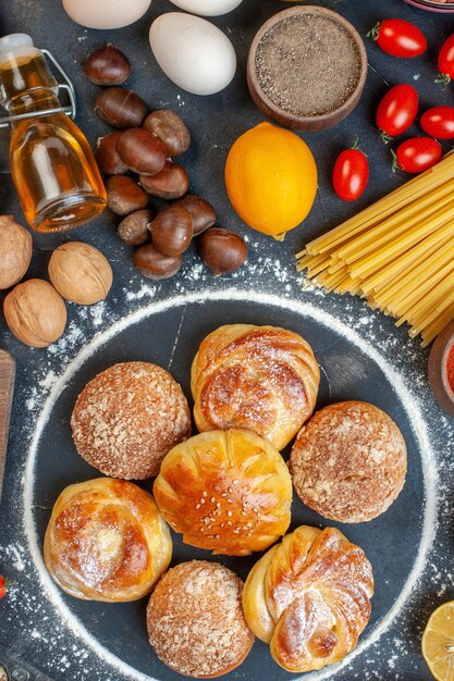 Ansicht von oben leckere süße Brötchen um Gemüse Nudeln Nüsse und Gewürze auf dunklem Hintergrund Zuckerkuchen Farbe Mahlzeit Diät rohes Gebäck Essen