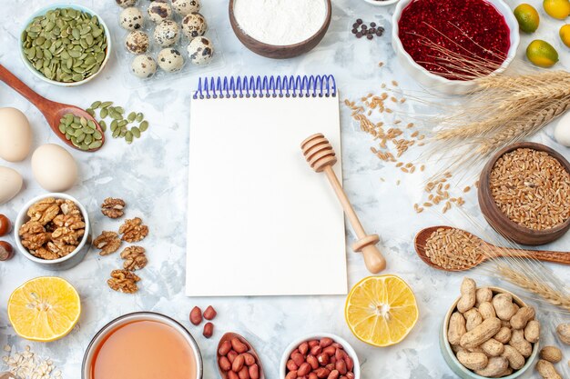 Kostenloses Foto ansicht von oben offener notizblock mit eiermehlgelee verschiedene nüsse und samen auf weißem nussfarbenkuchen süßer kuchen fotozuckerteig