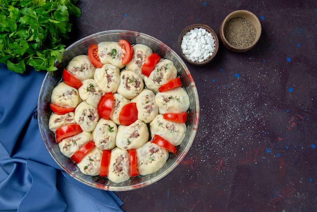 Kostenloses Foto ansicht von oben rohe teigstücke mit hackfleisch und tomaten auf dunklem essen küche salatteller küche foto farbe essen