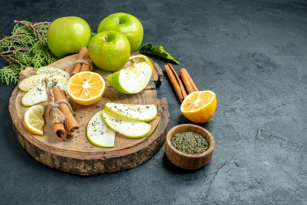 Ansicht von unten apfelscheiben zimtstangen und zitronenscheiben apfel auf holzbrett geschnitten zitronenzimt getrocknete minze in kleiner schüssel auf schwarzem tisch mit kopierraum