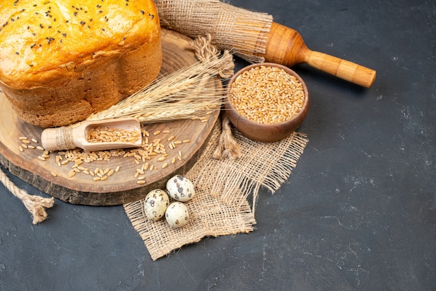 Ansicht von unten Brot mit Schwarzkümmel auf Naturholzbrett Weizenkörner in Schüssel Nudelholz Wachteleier auf Tisch mit Kopie Platz