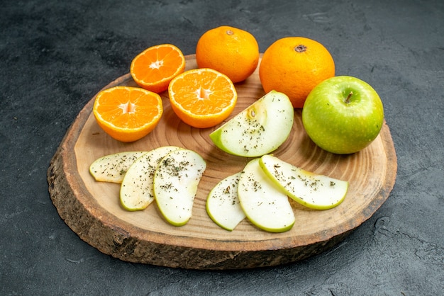 Ansicht von unten frisch geschnittene Äpfel und Orangen mit getrocknetem Minzpulver auf Holzbrett auf schwarzem Tisch