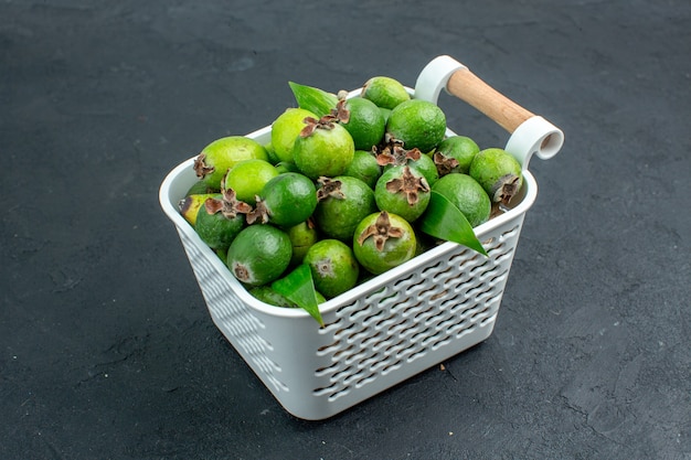 Ansicht von unten frische Feijoas auf Plastikkorb auf dunkler Oberfläche