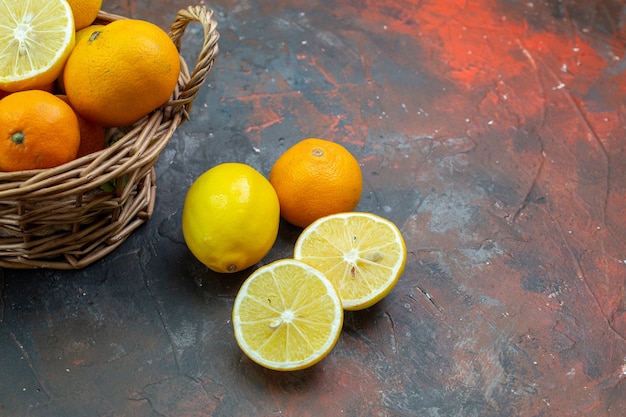 Ansicht von unten frische Mandarinen im Weidenkorb geschnittene Zitronen auf dunkelrotem Boden mit freiem Platz