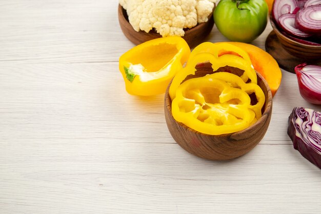 Ansicht von unten frisches Gemüse geschnittene Zwiebel geschnittene gelbe Paprika in Schalen auf weißem Holztisch mit freiem Platz