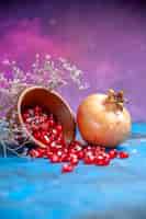 Kostenloses Foto ansicht von unten granatapfelkerne in einer schüssel ein granatapfel auf lila freiem platz
