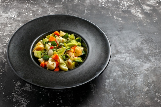 Ansicht von unten grüner Tomatensalat auf ovalem Teller auf dunklem Hintergrund