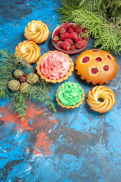 Ansicht von unten Himbeerkuchen kleine Törtchen Keksschüssel mit Himbeeren auf blauem Tisch Freiraum