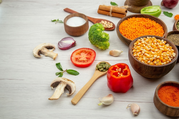 Kostenloses Foto ansicht von unten holzschalen mit kürbiskernen linsen schwarze und rote paprika schalen holzlöffel brokkoli zimt auf holztisch