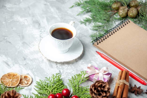 Ansicht von unten Kiefer Zweige Tasse Tee kleine Geschenke Weihnachtsbaum Spielzeug Notizbuch Bleistift auf Grau