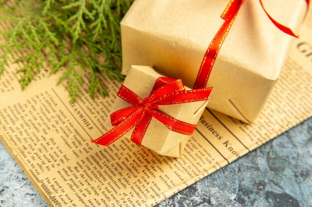 Ansicht von unten kleine Geschenke mit rotem Band auf Zeitung auf Dunkelheit gebunden