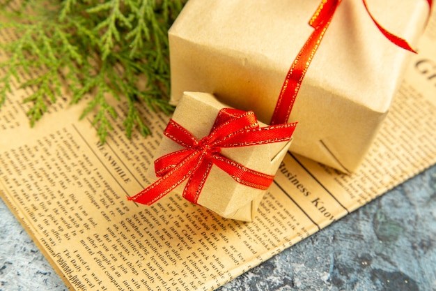 Ansicht von unten kleine Geschenke mit rotem Band auf Zeitung auf dunklem Hintergrund gebunden