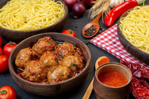 Ansicht von unten leckere Fleischbällchensuppe in Schüssel Spaghetti in Schüssel Holzlöffel rote Tomaten auf Tisch