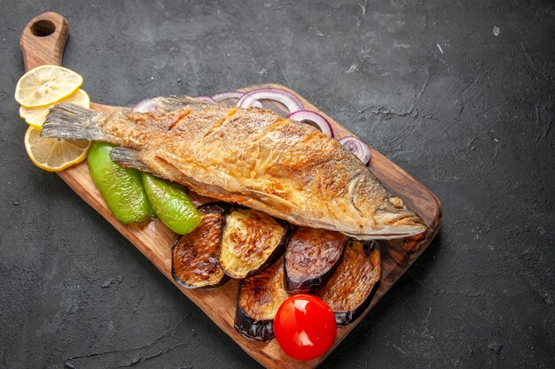 Ansicht von unten leckeren Fisch braten gebratene Auberginen Zwiebel auf Holz Servierbrett auf dunklem Hintergrund