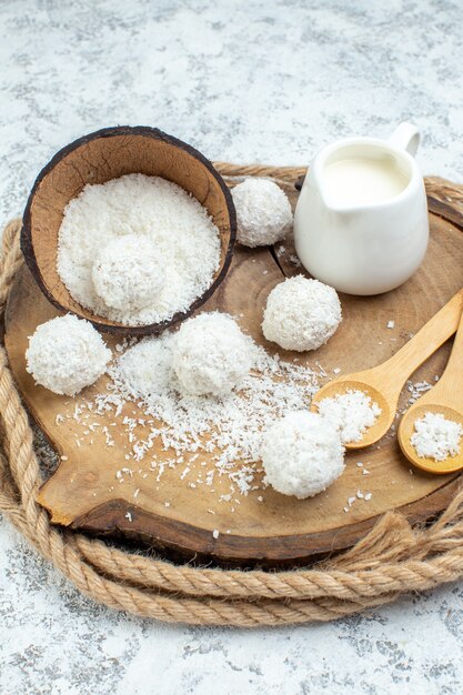 Ansicht von unten Milchschale Kokospulver Schüssel Holzlöffel Kokoskugeln auf Holzbrett auf grauem Hintergrund