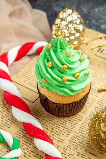 Ansicht von unten Mini-Cupcake-Weihnachtsbonbon-Weihnachtsverzierungen auf Zeitungsbeige-Tüll-Schal auf Dunkelheit