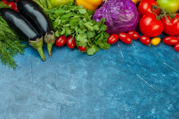 Ansicht von unten Obst und Gemüse Kirschtomaten Auberginen Tomaten Rotkohl Koriander auf blauem Tisch mit freiem Platz